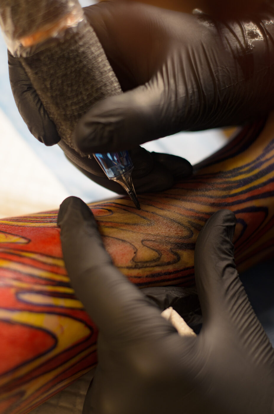 Mãos da Piettra com luvas pretas tatuando